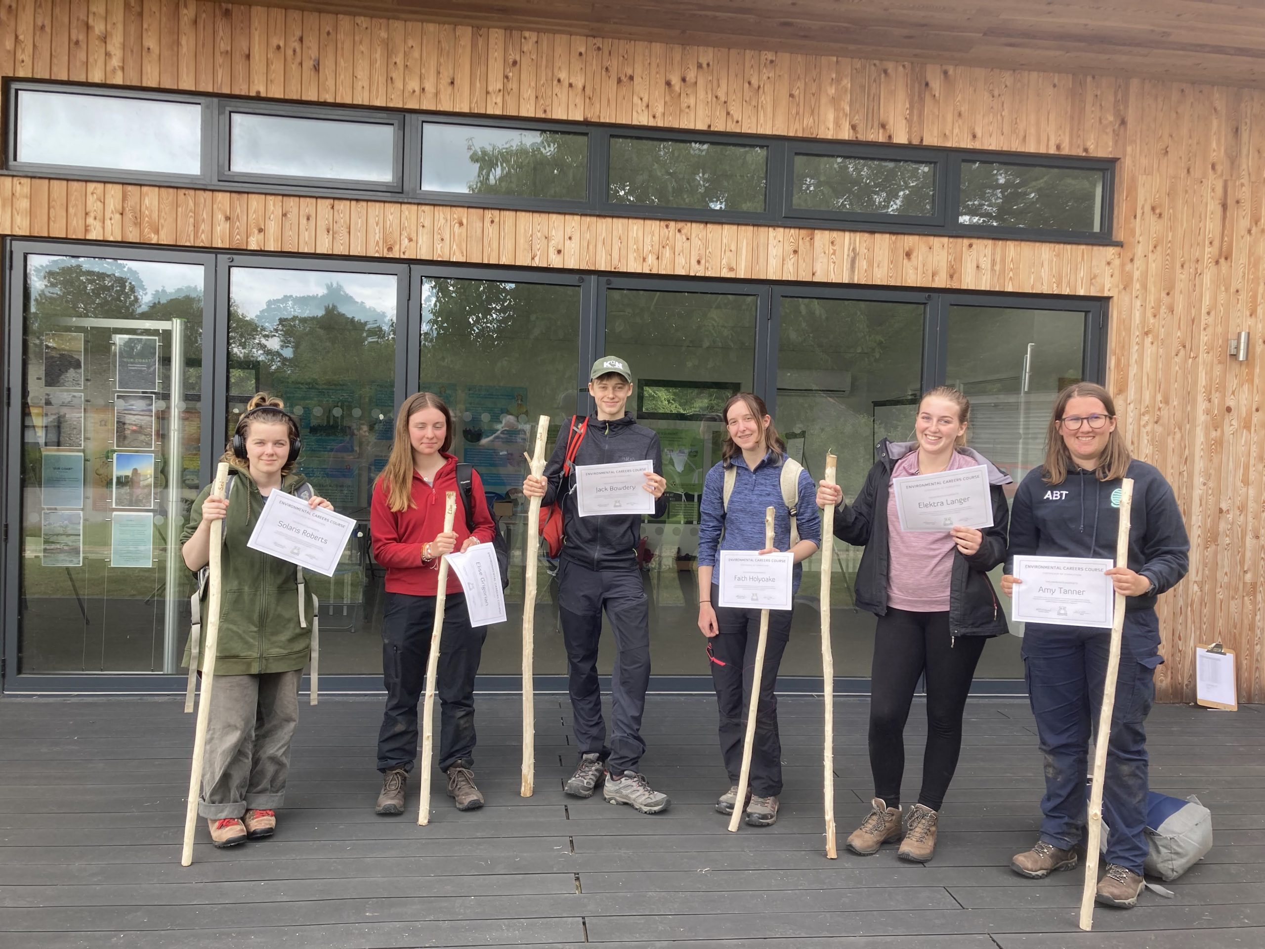 Six young people holding shepherding sticks they carved themselves and certificates