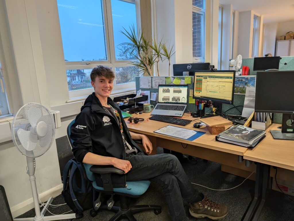 A man in NPA uniform sat at a desk with various images of houses and plans on the screen