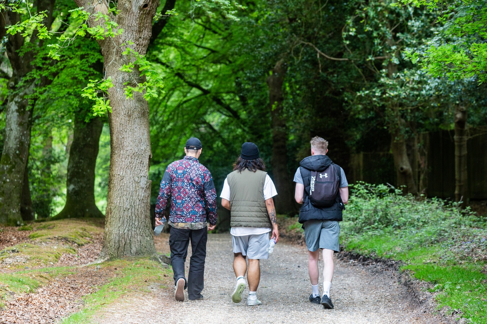 Three men walking along a path in a woodland