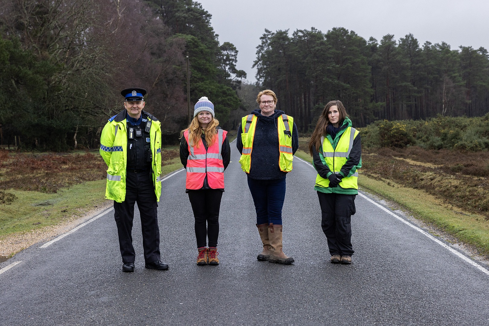 Four people in high vis stood together on a road