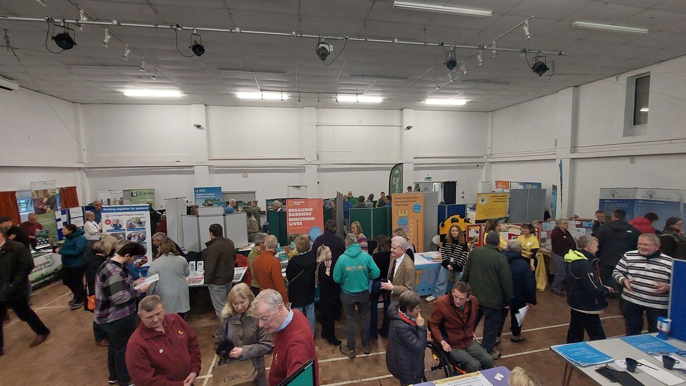 New Forest National Park volunteer Fair 2025 at Brockenhurst Village Hall full of stall and display boards with many people throughout the hall talking with stallholders
