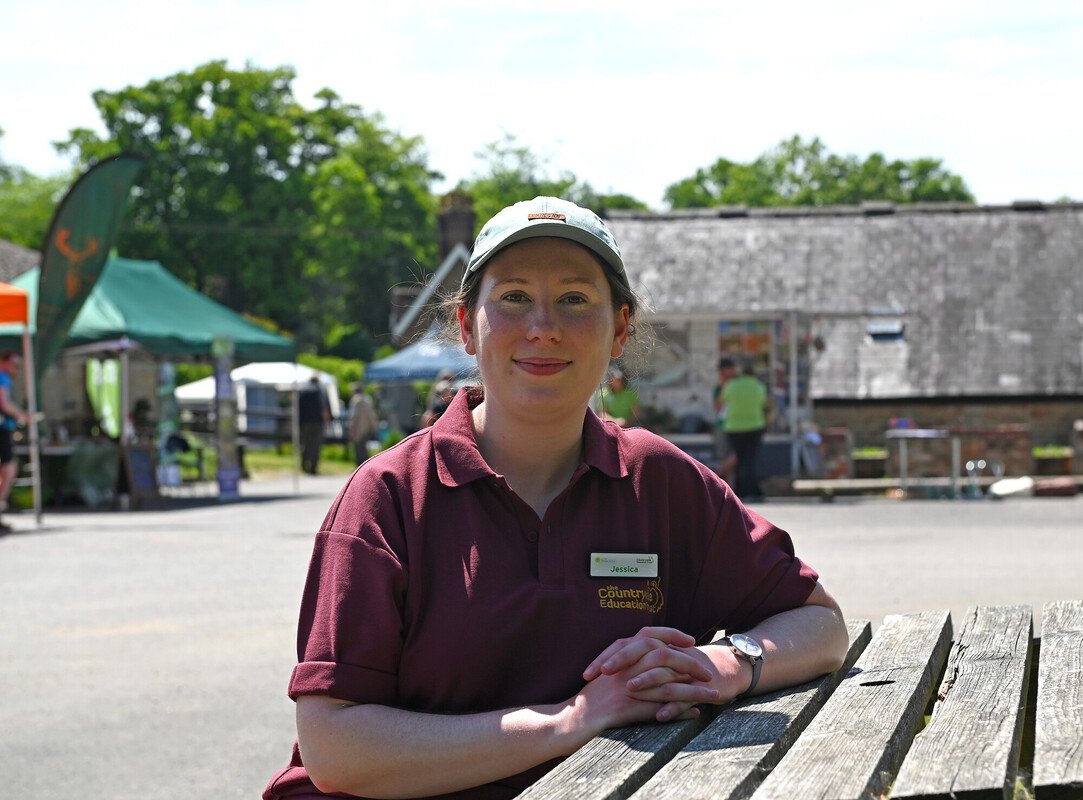 CET staff member Jessica sat at a table outdoors with hands clasped together