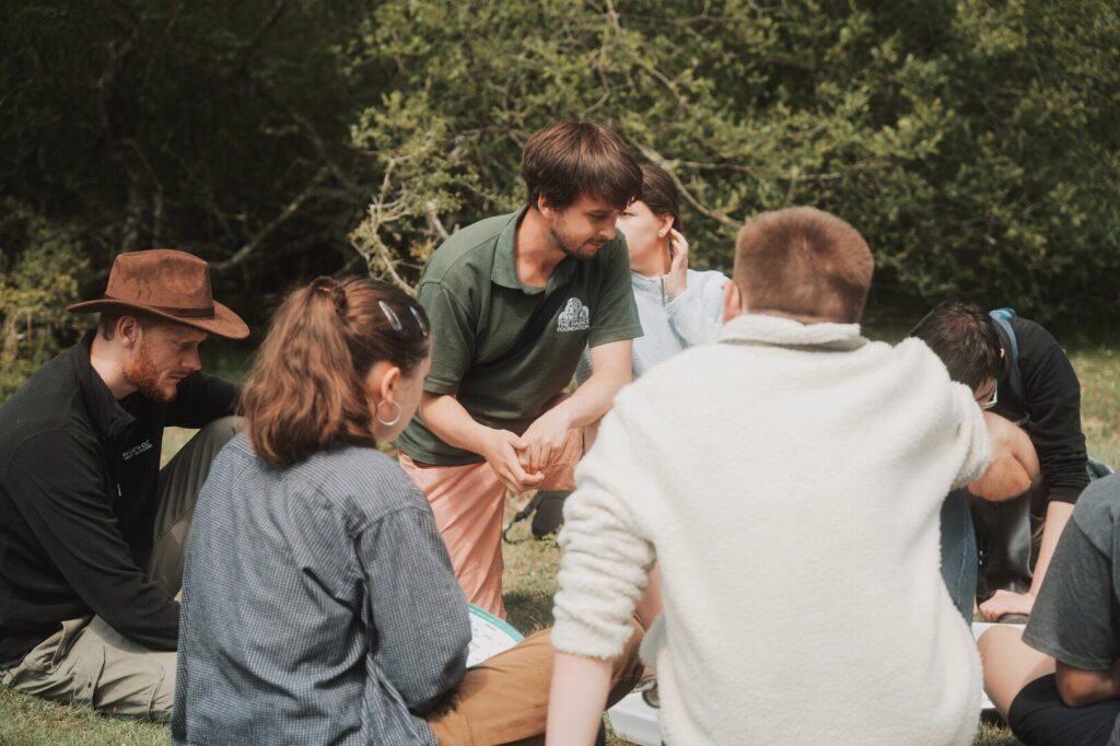 A group of young peopel supported by YouCAN sit in a green area in the New Forest.