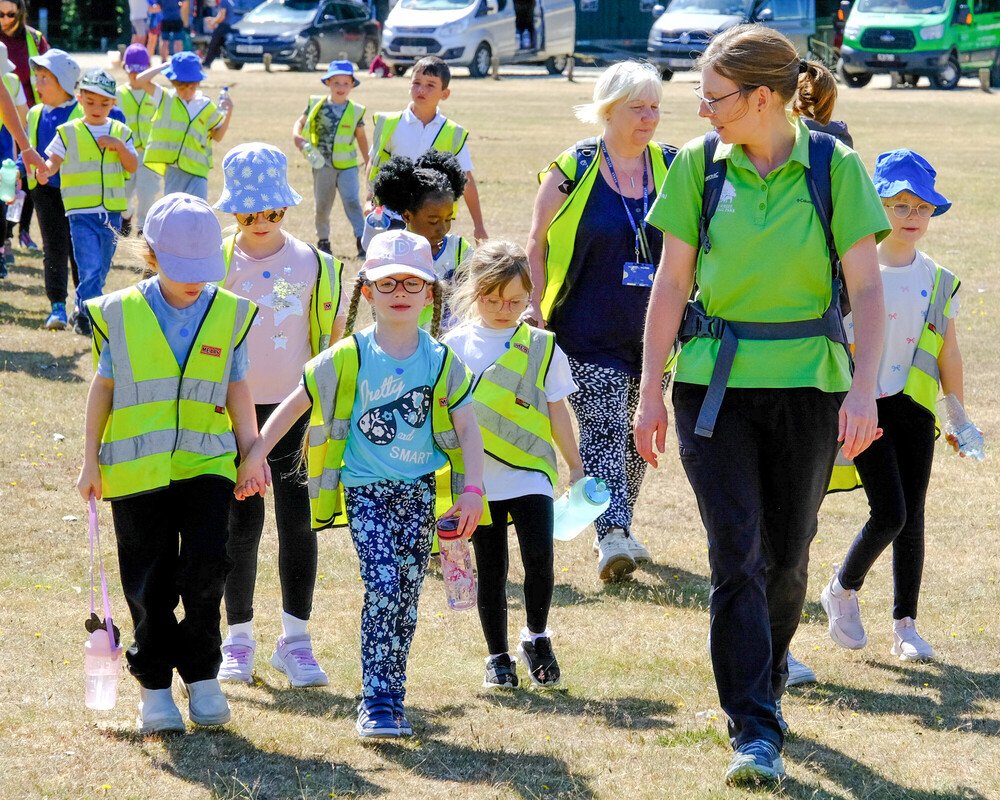 A group of school children walking in a field on a sunny day with an NPA education officer