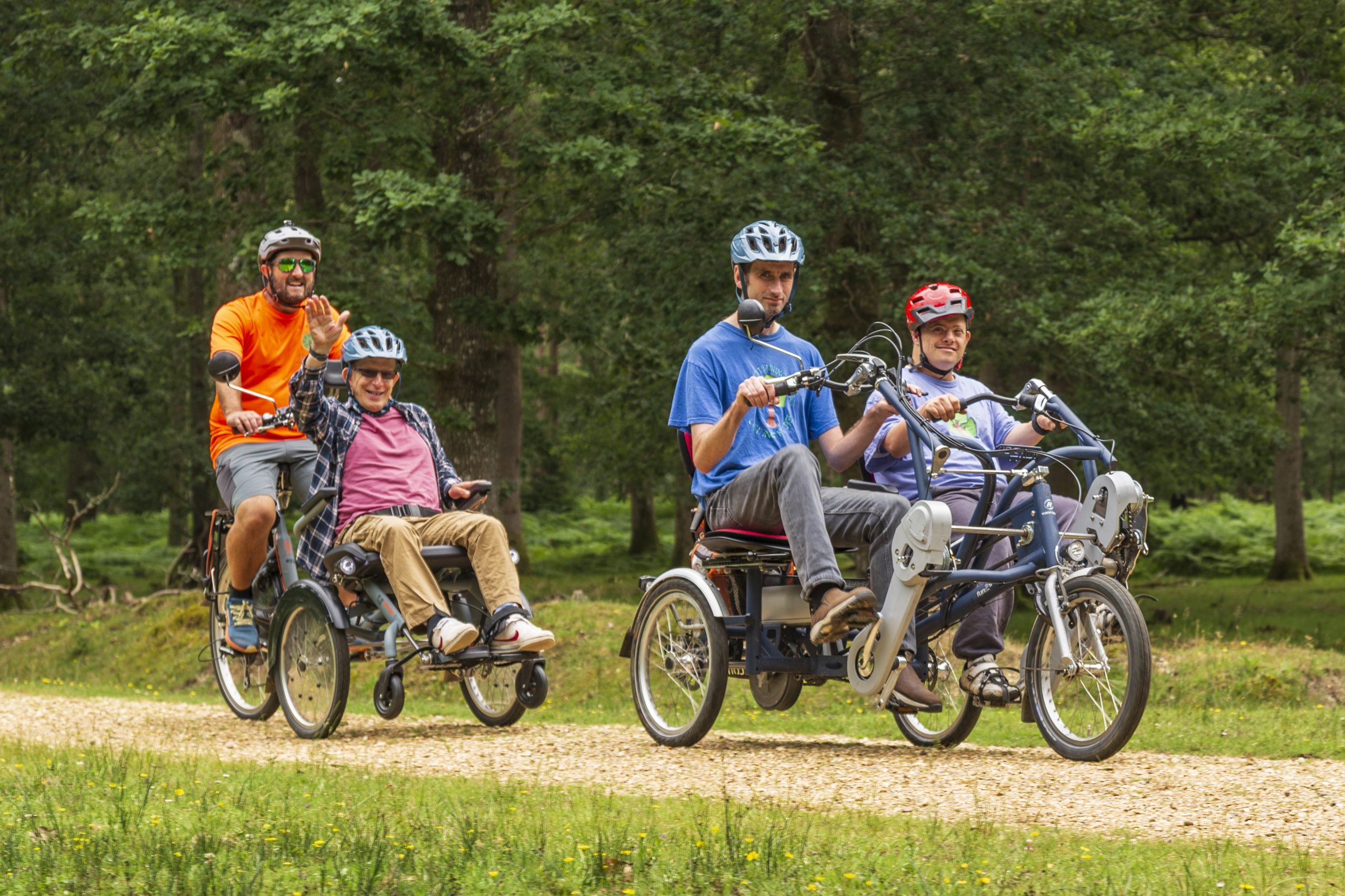 PEDALL operation lead Gareth Jones operating a ambulatory cycle with a passenger in front. Two riders cycle alongside in a tandem bike.
