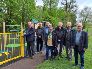 Cllr Keith Mans and parish council members at a ribbon-cutting for the new Queen Elizabeth II play area by a yellow gate