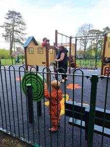 Families and children playing at Queen Elizabeth II play area in Wharton’s Lane, Ashurst, with climbing frames and playhouse