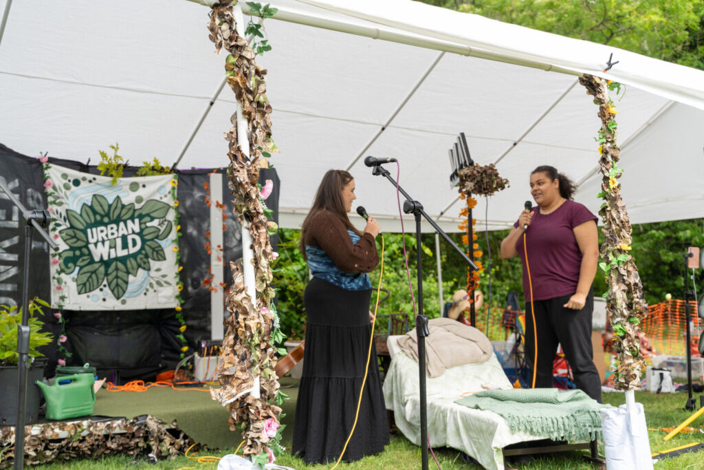 Actors stand in a tent at a festival performing scenes from Bringing the Outside In.