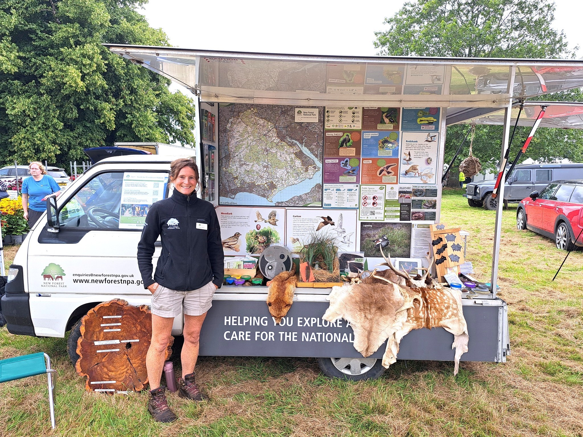 New Forest National Park staff member beside a mobile information van with wildlife posters, maps, and animal hides on display