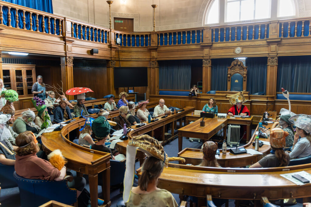 A council chamber full of people in animal and plant costumes