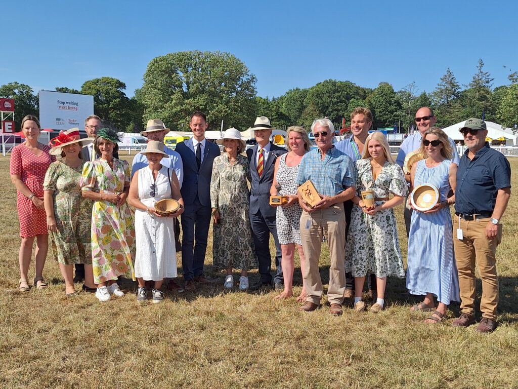 New Forest Awards 2026 winners group photo outdoors at a showground, several holding wooden trophies and bowls