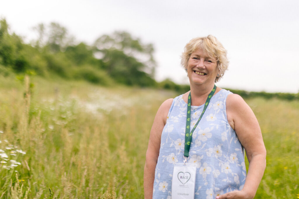 A woman standing in a wildflower meadow smiling