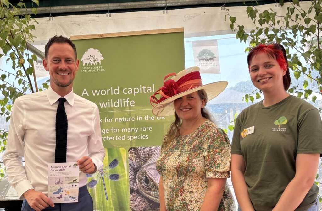 Stephen Morgan MP, Alison Barnes and Abi Tebb pose by a New Forest National Park banner, Morgan holding a leaflet