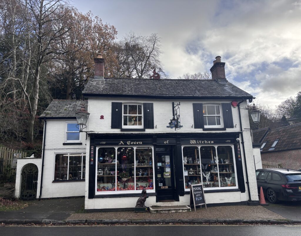 Front of A Coven of Witches shop in Burley, a white building with black shutters and large display windows of figurines