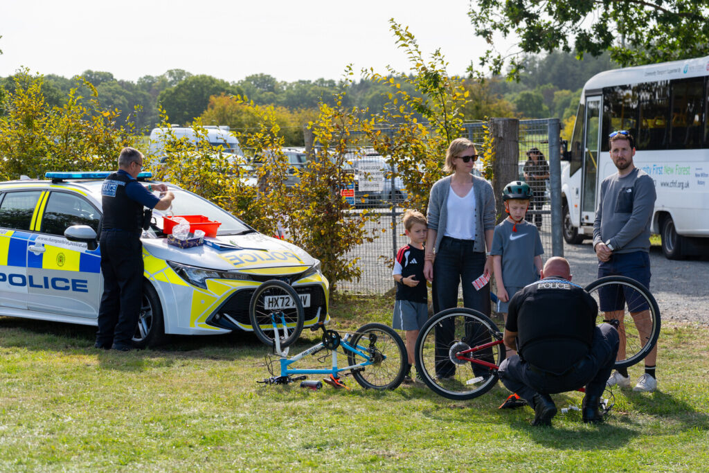 A police officer marking a bike at a public cycling event next to a police car