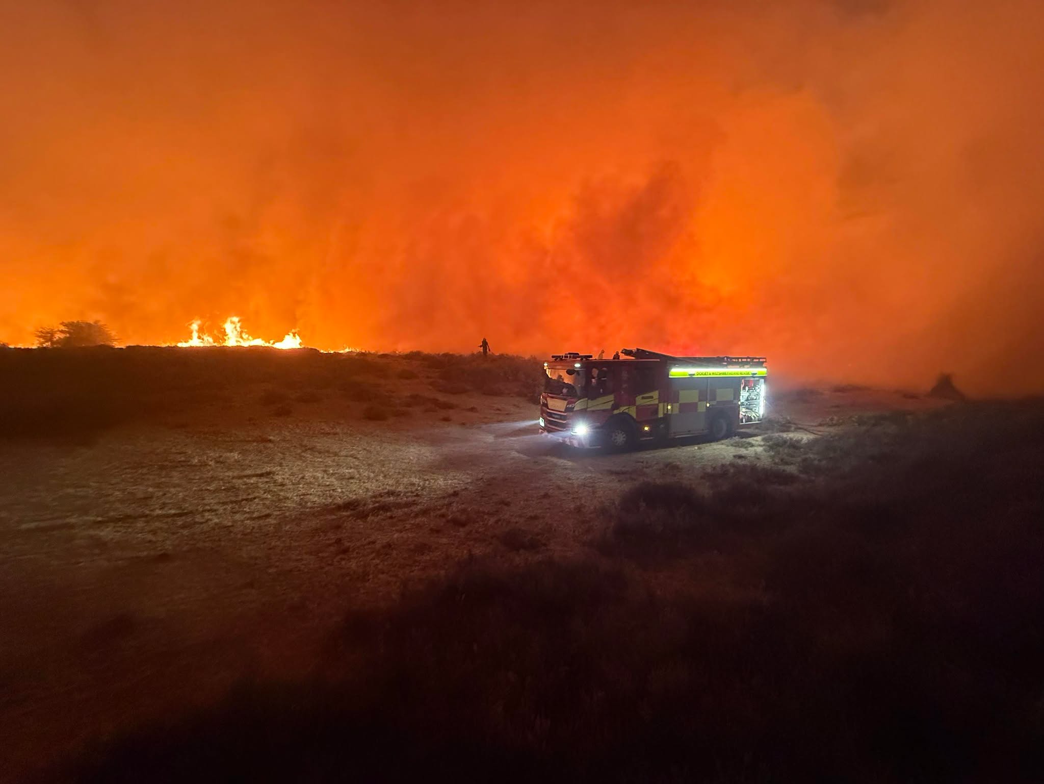 Fire engine on a track as flames and thick orange smoke spread across moorland during the New Forest A31 wildfire